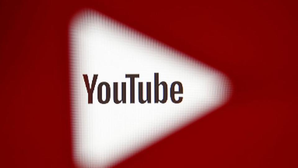 A 3D-printed YouTube icon is seen in front of a displayed YouTube logo in this illustration.