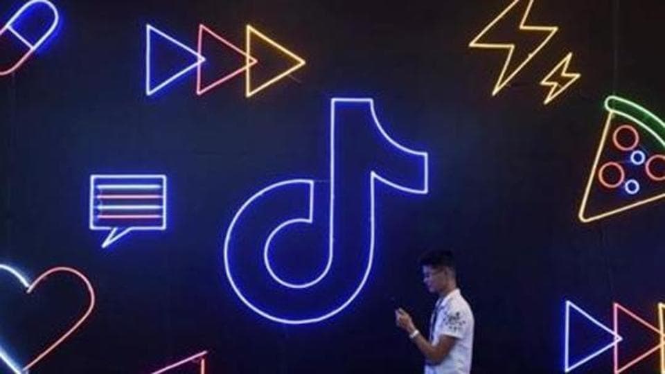 FILE PHOTO: A man holding a phone walks past a sign of Chinese company ByteDance's app TikTok, known locally as Douyin, at the International Artificial Products Expo in Hangzhou, Zhejiang province, China October 18, 2019. REUTERS/Stringer