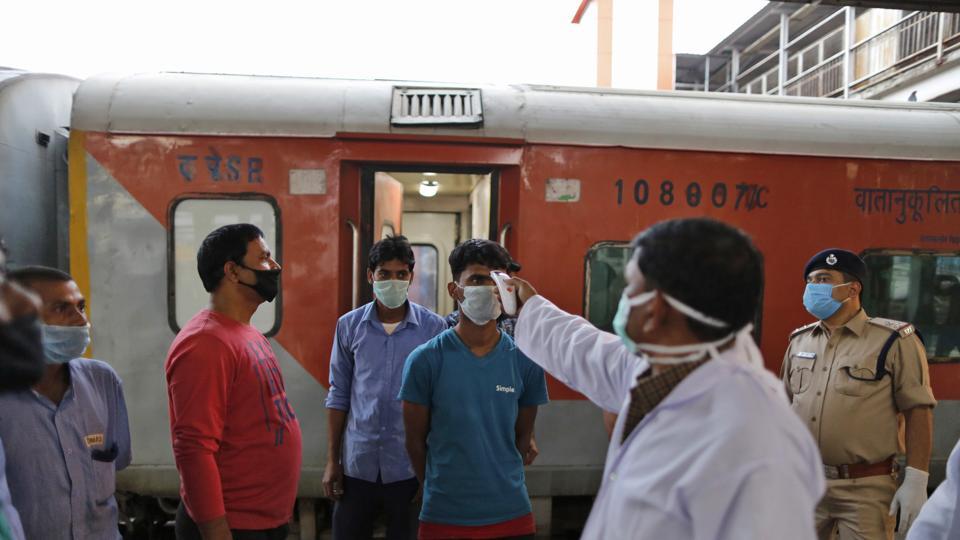 A railways official checks temperature of a railway worker in Prayagraj, India, Tuesday, March 24, 2020. Indian Prime Minister Narendra Modi Tuesday announced a total lockdown of the country of 1.3 billion people to contain the new coronavirus outbreak. For most people, the new coronavirus causes only mild or moderate symptoms. For some it can cause more severe illness.