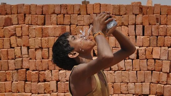 ఇటుక బట్టీల వద్ద అలసిపోయి నీళ్లు తాగుతున్న బాలకార్మికుడు