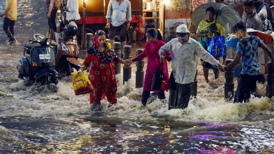 హైదరాబాద్‌లో వర్షపు నీటిలో రోడ్డు దాటుతున్న ప్రజలు