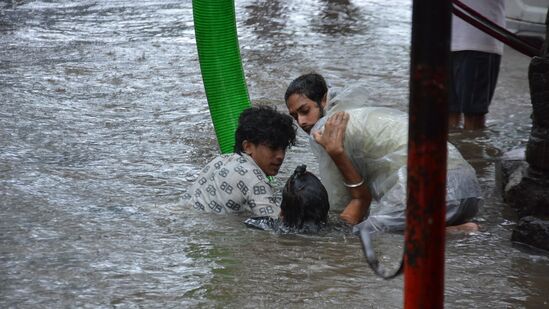 థానేలో నీట మునిగిన రోడ్డులో చిక్కుకున్న ప్రయాణికులు ఒకరికొకరు సహాయం చేసుకుంటున్న దృశ్యం