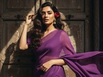 <p>Create a retro, vintage-inspired image—grainy yet bright—based on the uploaded picture. The girl should be draped in a perfect purple chiffon, Pinterest-style aesthetic saree. The vibe must capture the essence of a '90s movie 'baddie,' with dark brown, silky hair and a small flower tucked visibly into her hair, enhanced by a windy, romantic atmosphere. She is standing against an old wooden door, where deep shadows and dramatic contrasts add mystery and artistry to the scene, creating a moody yet enchanting cinematic effect. Her pose should suggest that she is adjusting her hair.</p>
